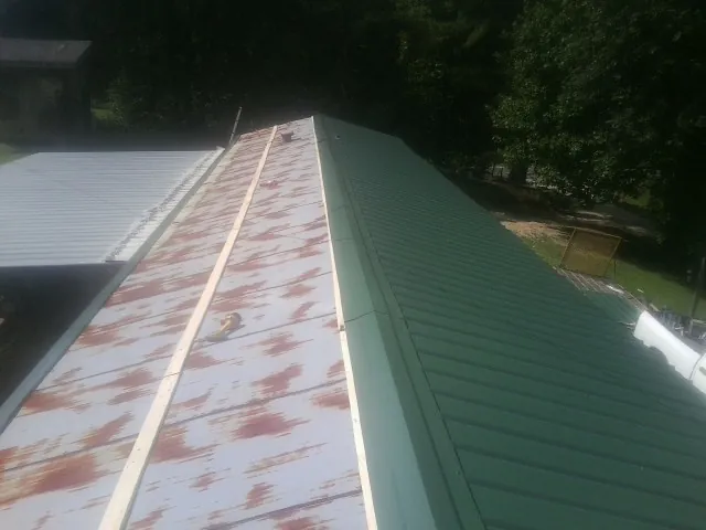 Old rusted panels beside newly installed green metal roofing — Wind Damage Roof Repair by Roofing Brothers in Rosenberg