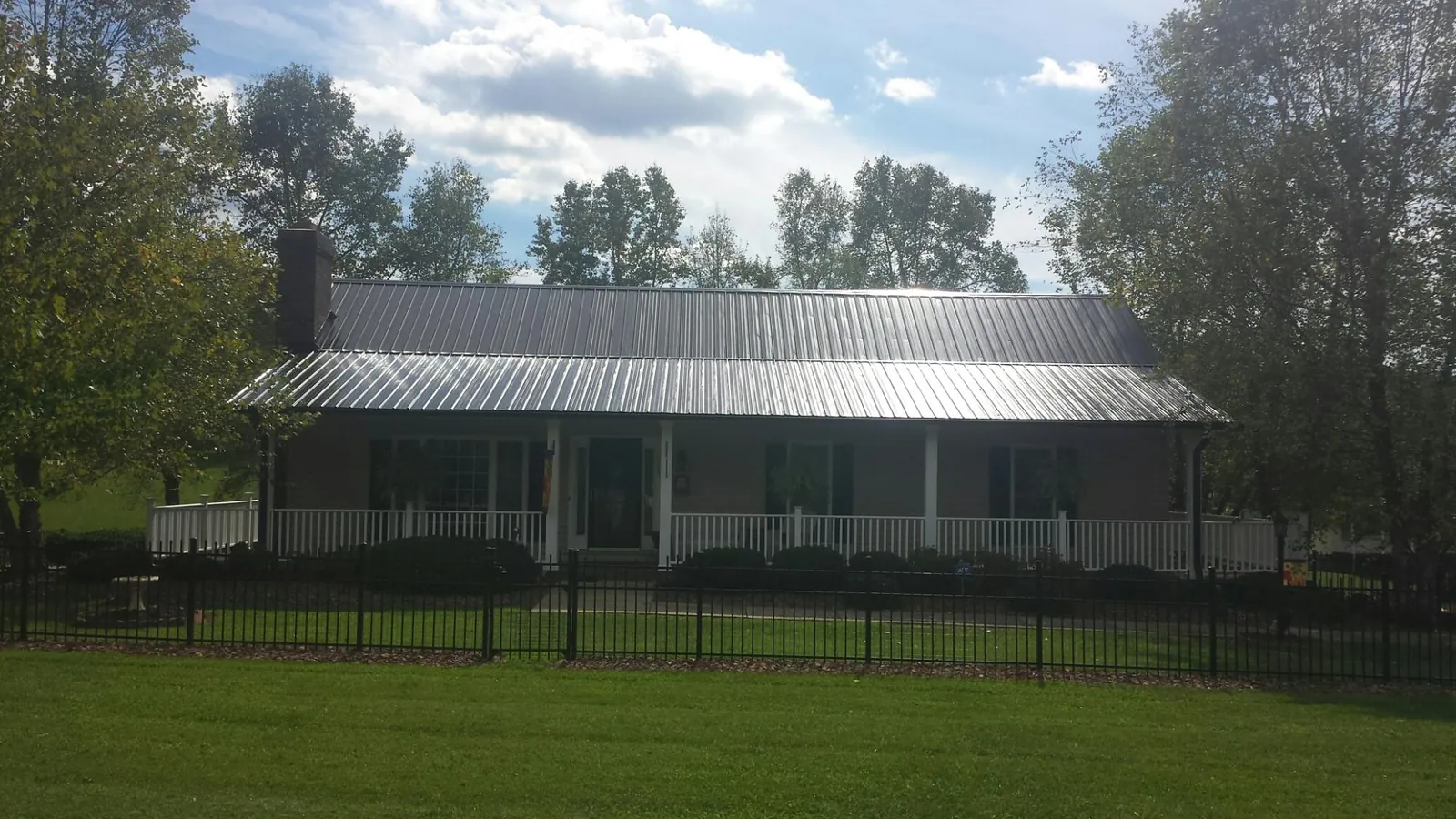Gray metal roof on a brick ranch with a full width front porch — Gutter Guard Installation work by our crew in Rosenberg