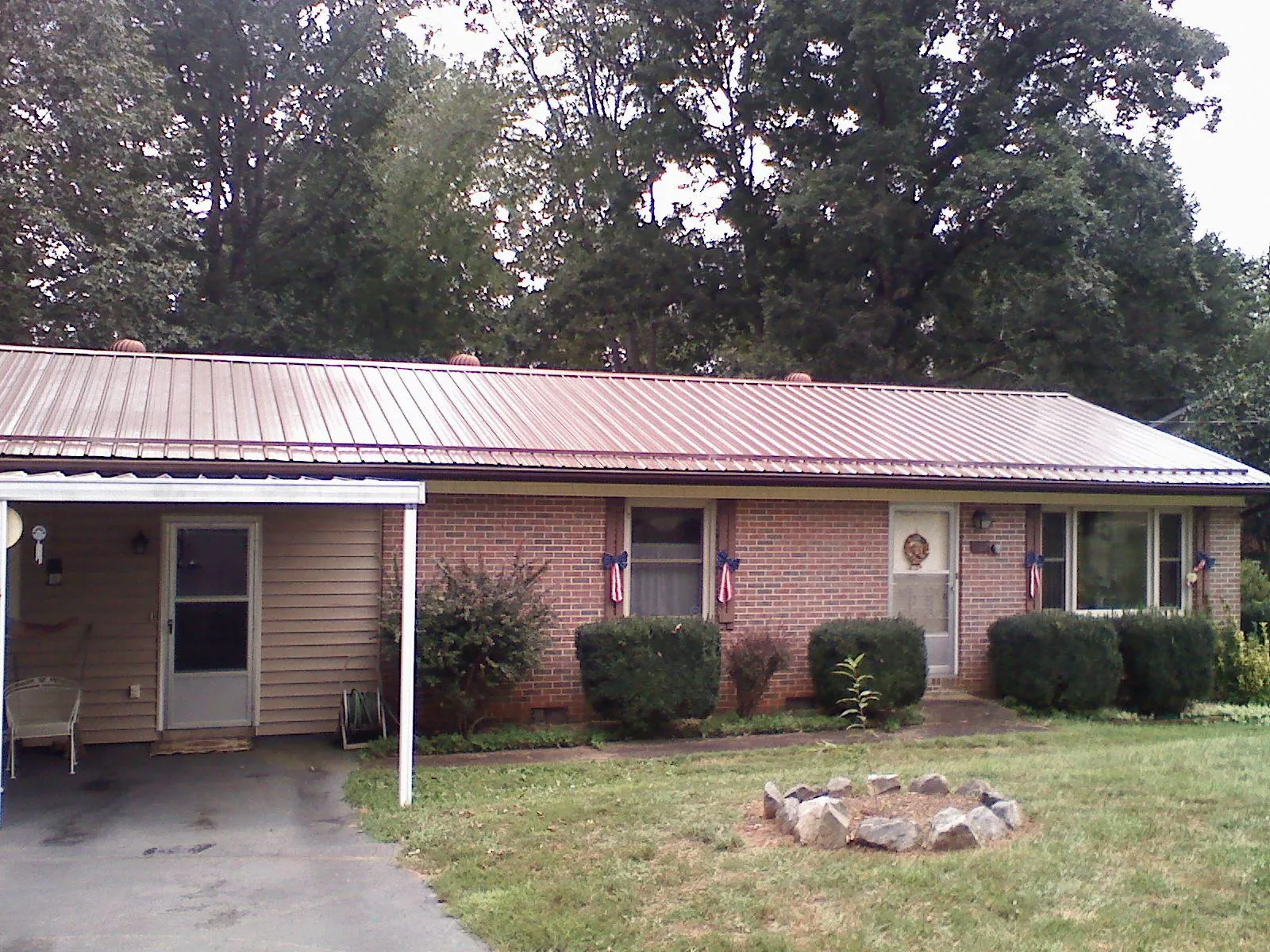 Bronze metal roof and carport on a brick ranch home — Roof Repair work by our crew in Rosenberg