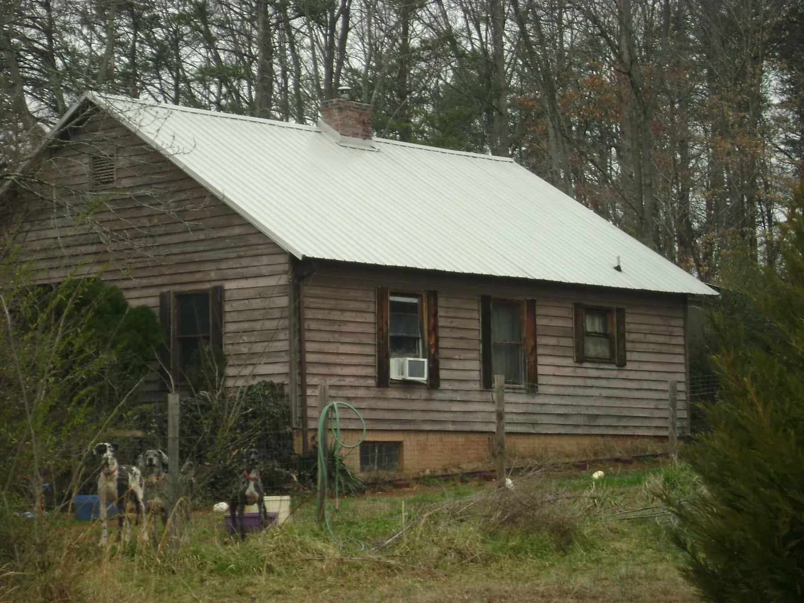 White metal roof on an old wood sided farmhouse, from a Asphalt Shingle Roof Repair job in Rosenberg