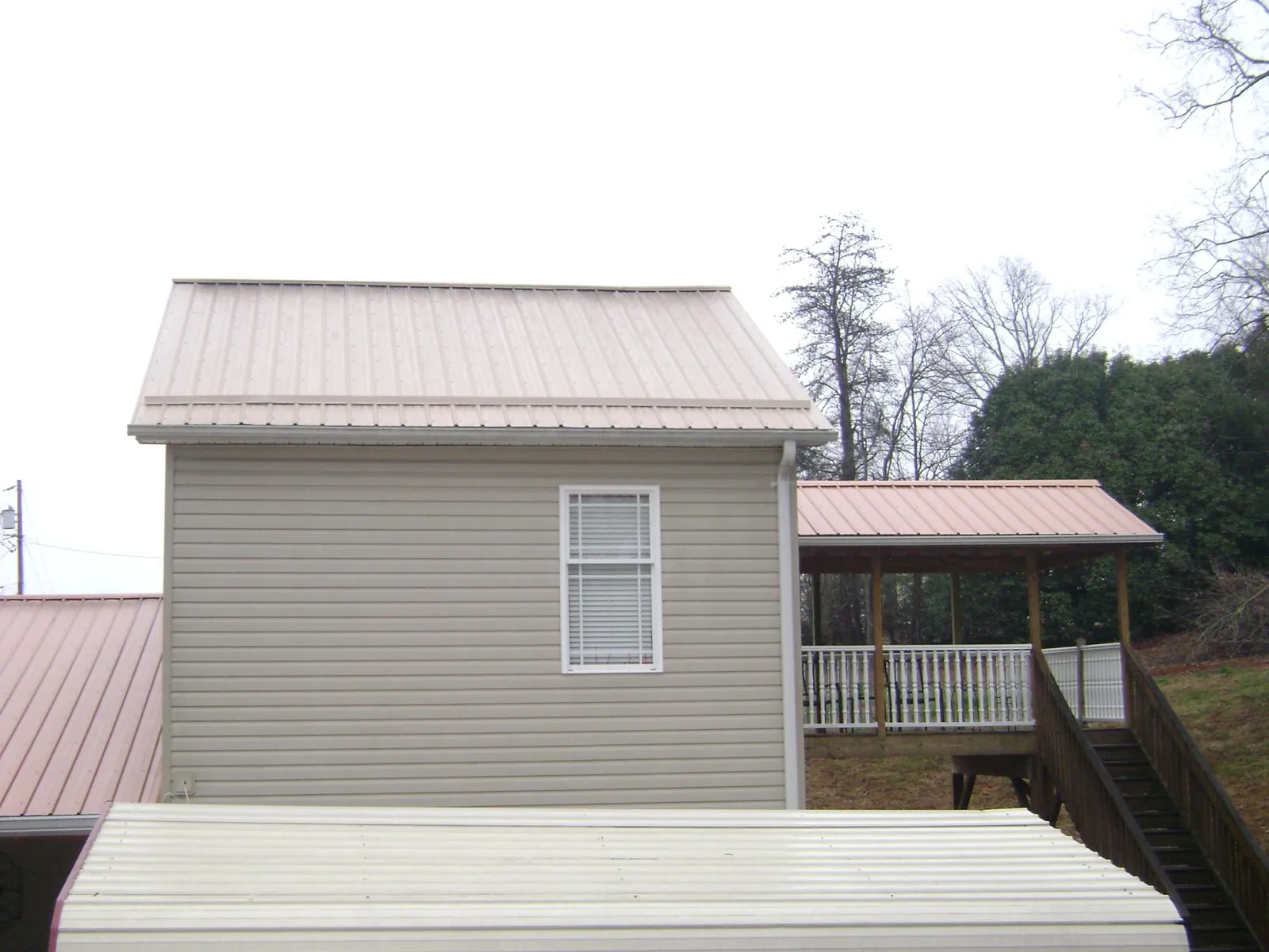 Tan metal roofs on a two story addition and attached porch, from a Roof Replacement job in Rosenberg